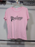A light pink short-sleeve t-shirt hanging on a hanger, featuring a black graphic print on the front that reads 'Mustangs 2025' with a horse silhouette. The shirt is photographed against a plain wall in what appears to be a storage or retail space.