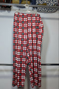 Red, white, and black plaid cropped pants hanging on a white plastic hanger from a metal clothing rack.