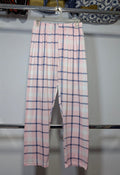 Pink and white plaid pants hanging on a metal rack against a white wall.