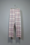 Pink and white plaid cropped pants hanging on a clear plastic hanger against a plain gray wall.