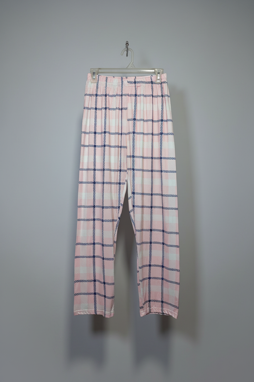 Pink and white plaid cropped pants hanging on a clear plastic hanger against a plain gray wall.