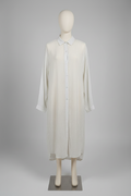A long-sleeve white button-front shirt dress with a pointed collar, displayed on a cream mannequin against a neutral gray studio background.