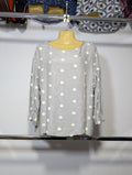 A light gray linen blouse with white polka dots, displayed on a yellow mannequin torso hanging on a metal rack.