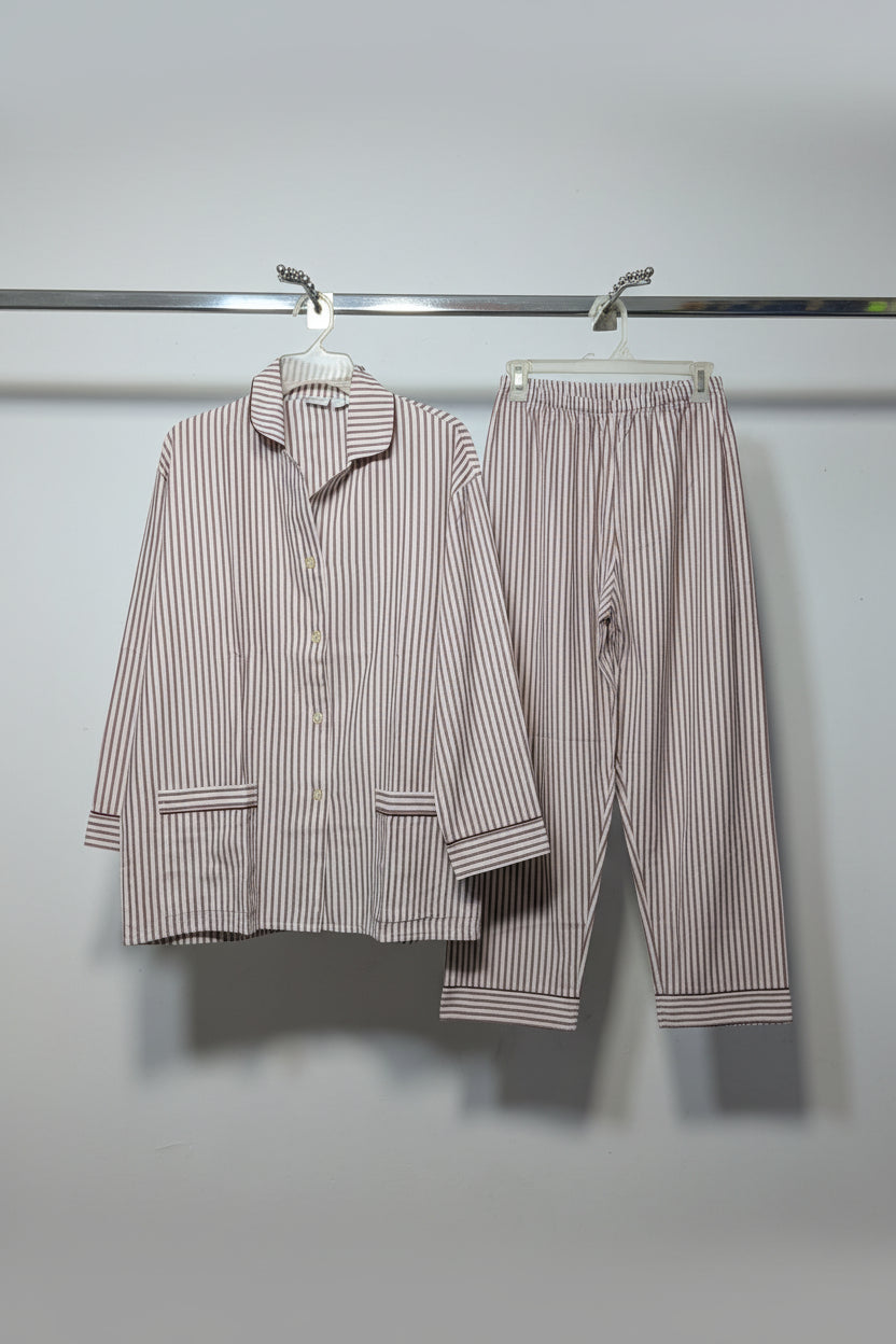 A two-piece pajama set consisting of a long-sleeve button-up shirt and matching pants, both featuring vertical red and white stripes, hanging on a rack.