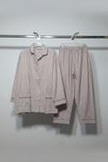 A two-piece pajama set consisting of a long-sleeve button-up shirt and matching pants, both featuring vertical red and white stripes, hanging on a rack.