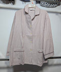 A long-sleeve button-front shirt with vertical brown and white stripes, hanging on a white plastic hanger against a light gray wall.