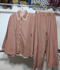 A matching two-piece set consisting of a long-sleeve button-up shirt and wide-leg pants, both in a dusty rose pink color with a small white polka dot pattern. The shirt features a contrasting white Peter Pan collar.