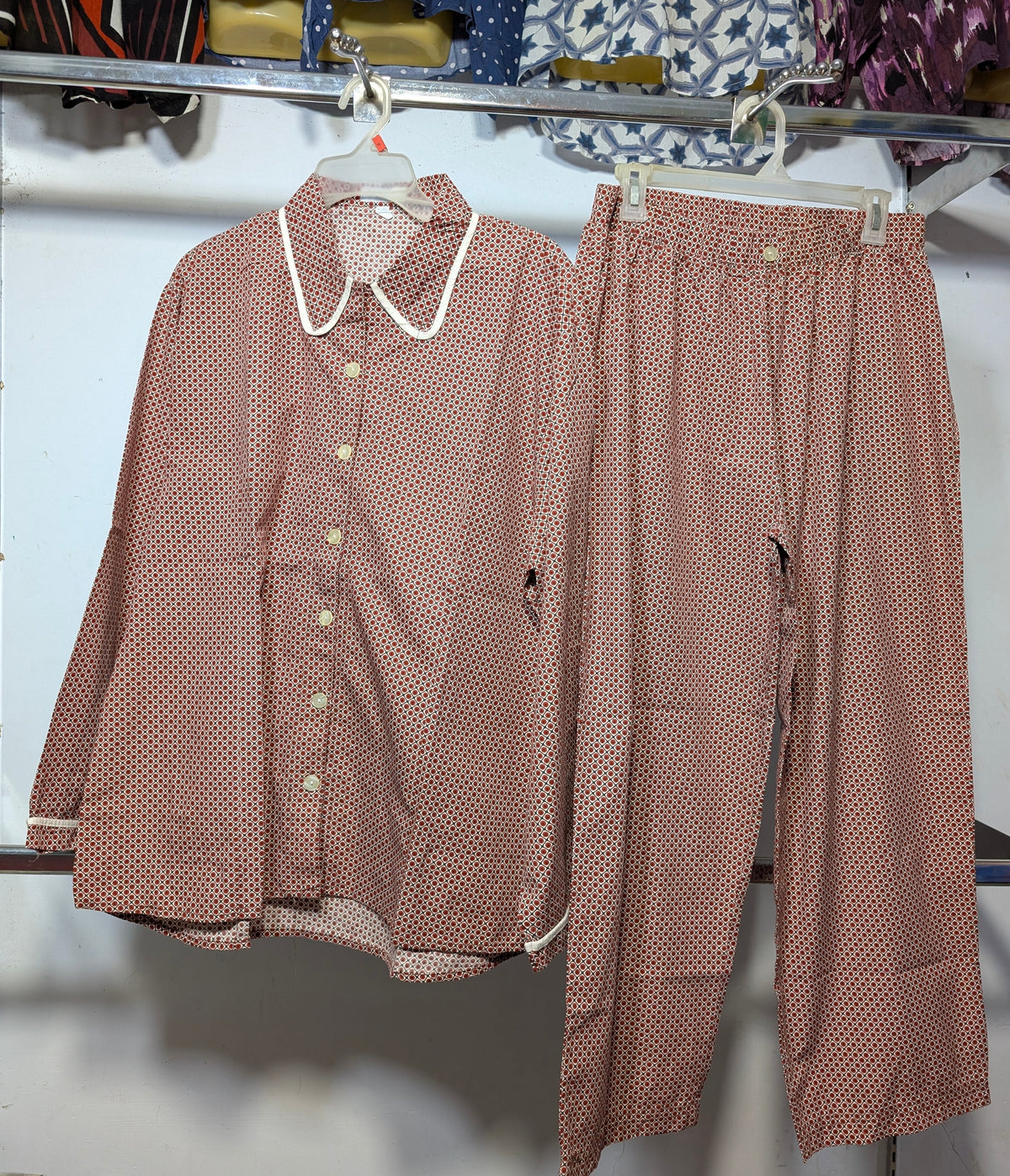 A matching two-piece set consisting of a long-sleeve button-up shirt and wide-leg pants, both in a dusty rose pink color with a small white polka dot pattern. The shirt features a contrasting white Peter Pan collar.