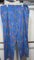 Blue cropped pants with a colorful floral and botanical print, hanging on a white plastic hanger against a white wall.