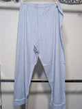 Light blue cropped pants with a relaxed, baggy fit and rolled cuffs, hanging on a white plastic hanger against a white wall.