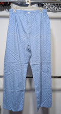 Light blue trousers with a small repeating geometric pattern, hanging on a white plastic hanger against a white wall.