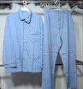 A light blue two-piece pajama set with a small repeating pattern, consisting of a long-sleeve button-front shirt and matching pants, hanging on a clothing rack.