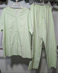 A light green two-piece pajama set consisting of a short-sleeve button-front top and matching pants, hanging on hangers from a clothing rack.