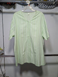 A light green short-sleeve button-up shirt with vertical white stripes, hanging on a white plastic hanger on a clothing rack.