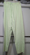 Light green striped cotton pajama pants hanging on a white plastic hanger against a white wall.
