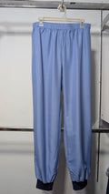 Light blue lightweight pants with an elastic waistband and cuffed ankles, hanging on a white plastic hanger against a plain light wall.
