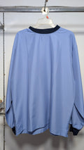 A light blue long-sleeve windbreaker jacket with a dark navy collar, hanging on a white plastic hanger from a metal clothing rack.