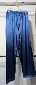 Blue satin cropped pants hanging on a white plastic hanger from a metal clothing rack against a white wall.