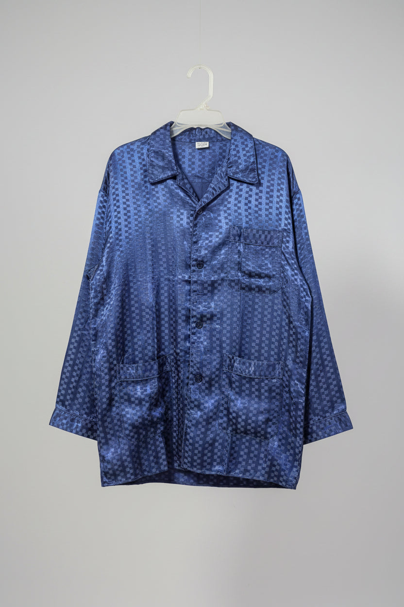 Blue patterned shirt on a hanger against a white wall