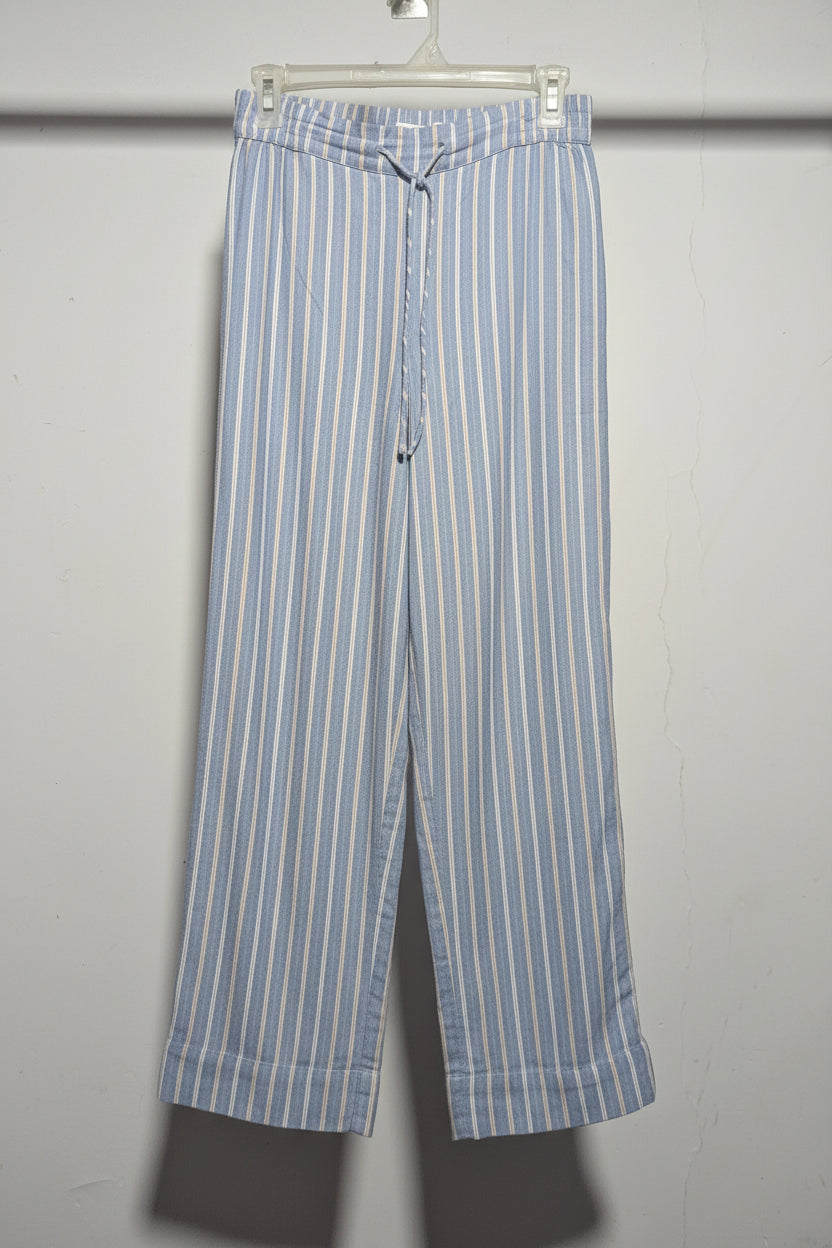 Blue and white striped pants hanging on a rack against a white wall.