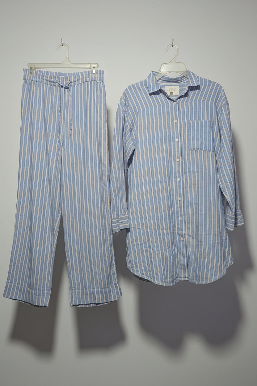 Striped shirt and pants hanging on a rack with other clothing items.