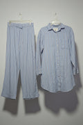 Striped shirt and pants hanging on a rack with other clothing items.