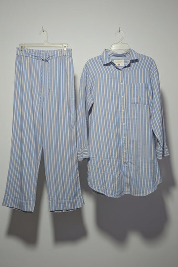 Striped shirt and pants hanging on a rack with other clothing items.