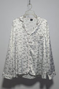 Floral-patterned blouse on a hanger against a gray background