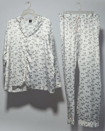 Floral-patterned shirt and pants hanging on a rack against a white wall.