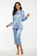 Woman wearing a blue satin pajama set on a white background