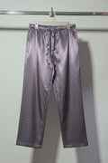 Striped shirt and pants hanging on a rack against a plain wall.