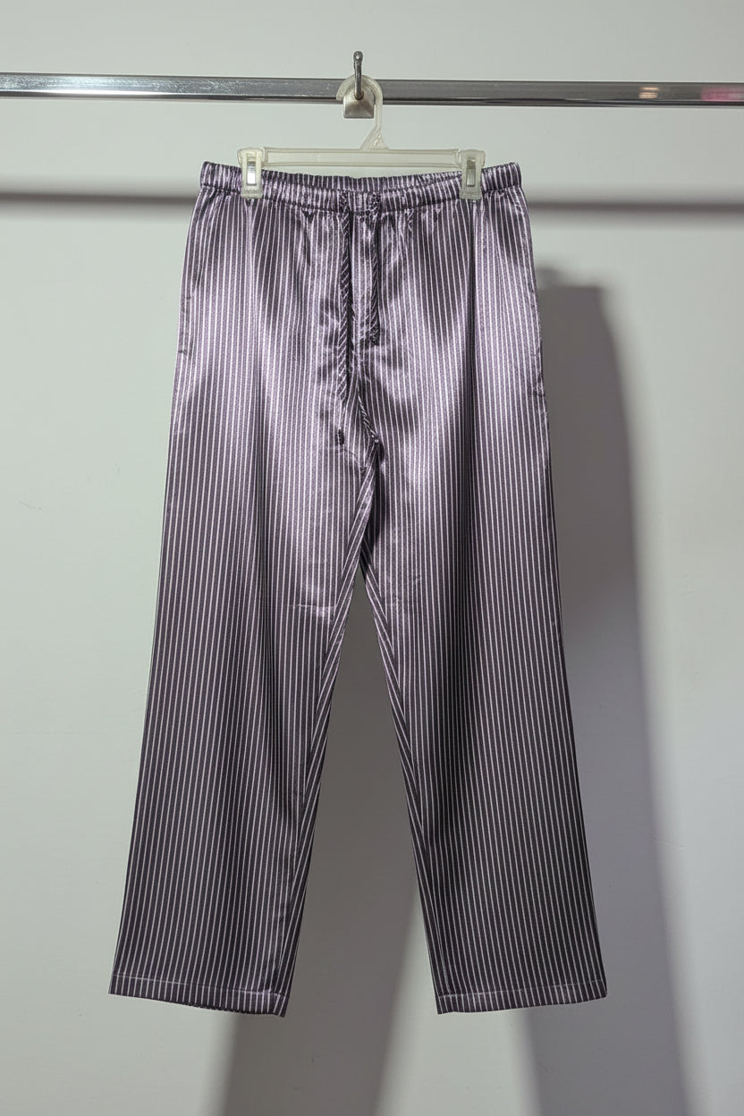 Striped shirt and pants hanging on a rack against a plain wall.