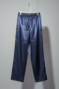 Navy satin pants hanging on a white hanger against a gray background