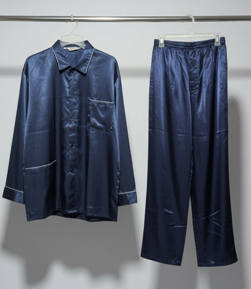 Navy satin pajama set hanging on a rack against a white wall.