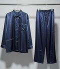 Navy satin pajama set hanging on a rack against a white wall.