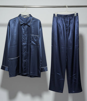Navy satin pajama set hanging on a rack against a white wall.