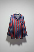 Striped shirt and pants hanging on a rack against a white wall.
