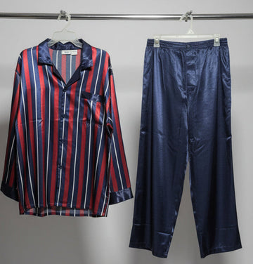 Striped shirt and satin pants hanging on a rack with a white wall background.