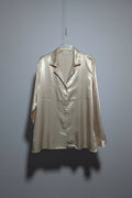 Light-colored satin jacket on a hanger against a plain background