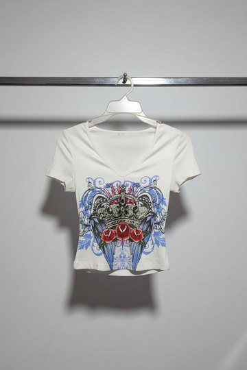 White t-shirt with a graphic design of roses and skulls on a hanger.