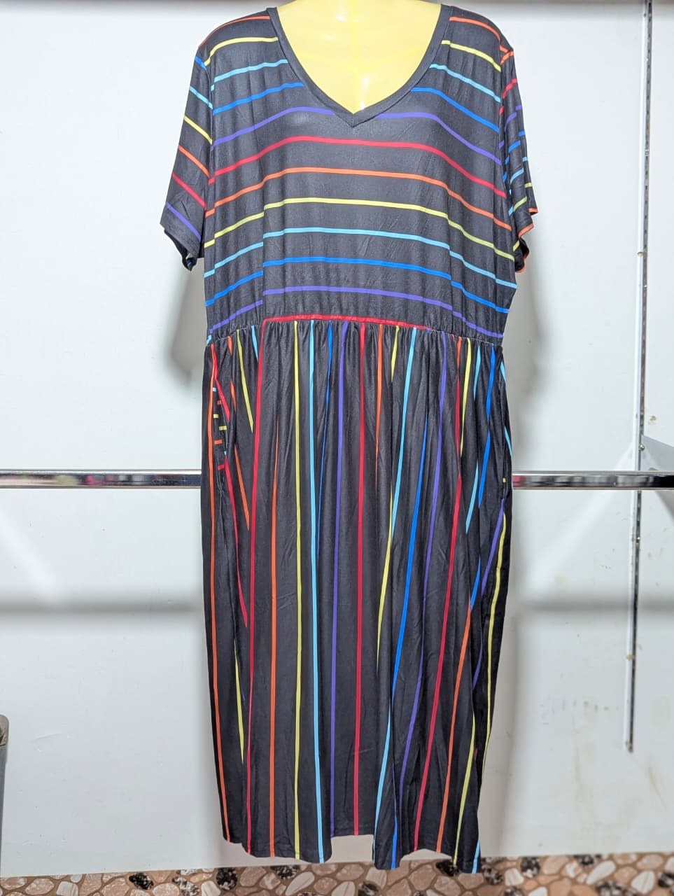 Colorful striped dress on a mannequin against a white wall.