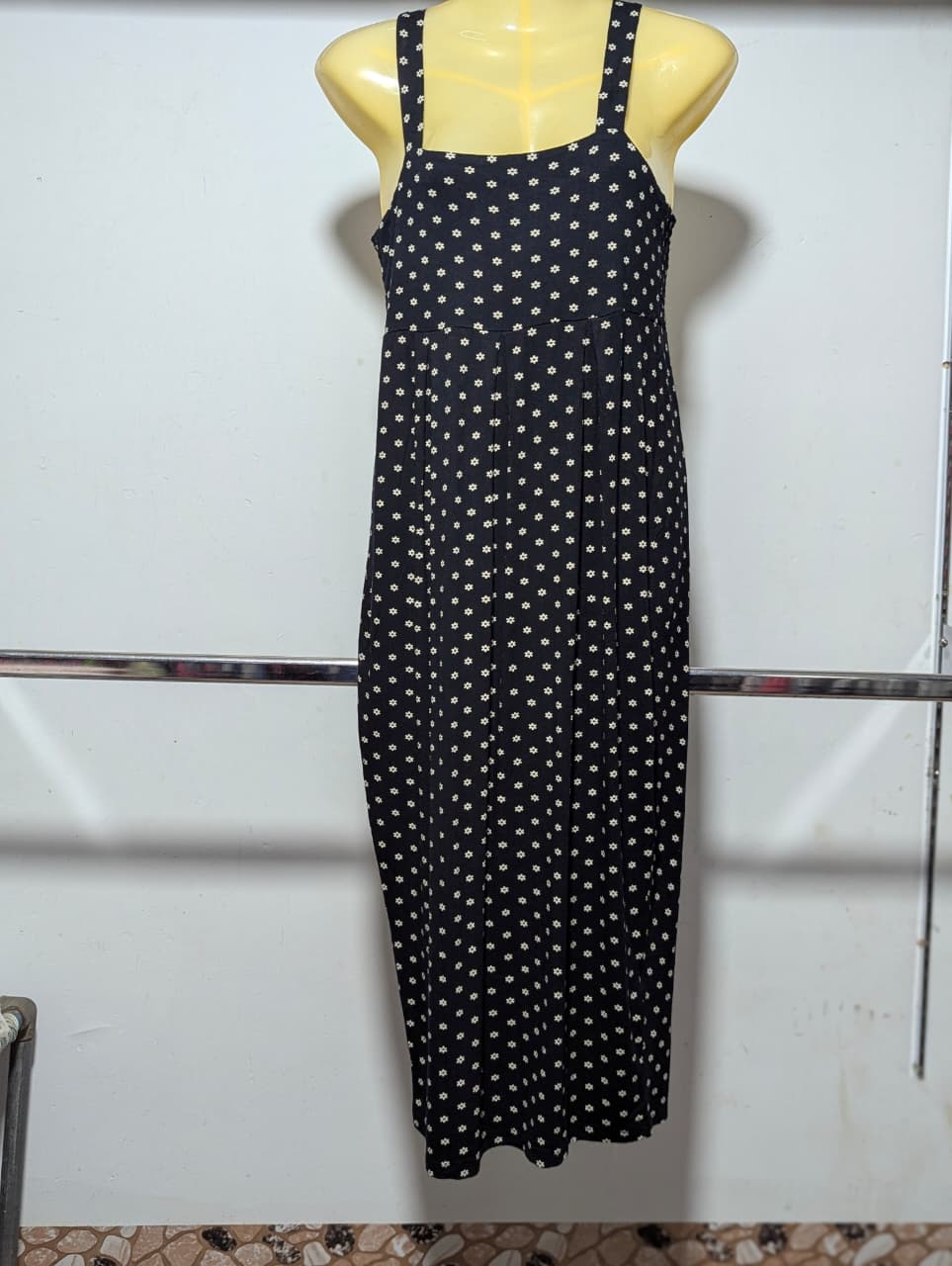 Black polka dot dress on a mannequin against a white wall.