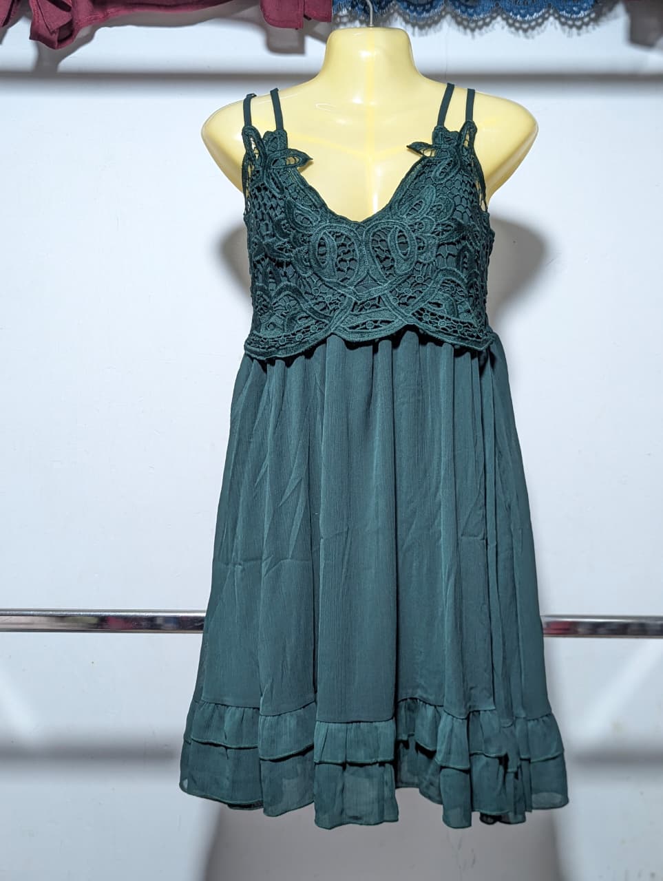 Teal dress with lace detailing on a mannequin against a white background