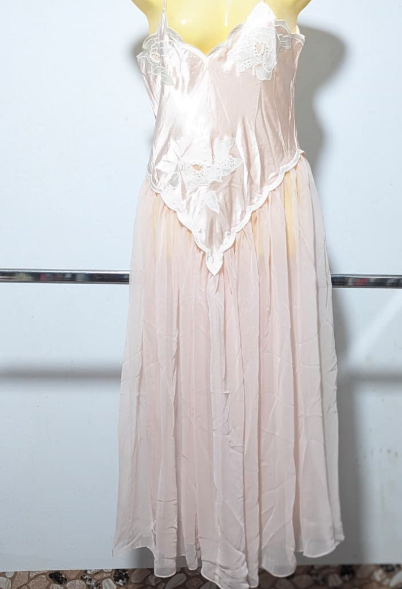 Light pink nightgown on a mannequin against a white wall.