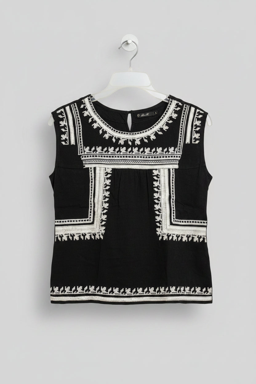 Black dress with white embroidery on a hanger against a colorful background