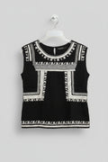 Black dress with white embroidery on a hanger against a colorful background