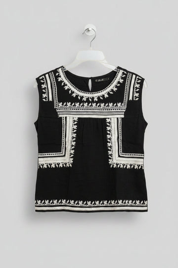 Black dress with white embroidery on a hanger against a colorful background