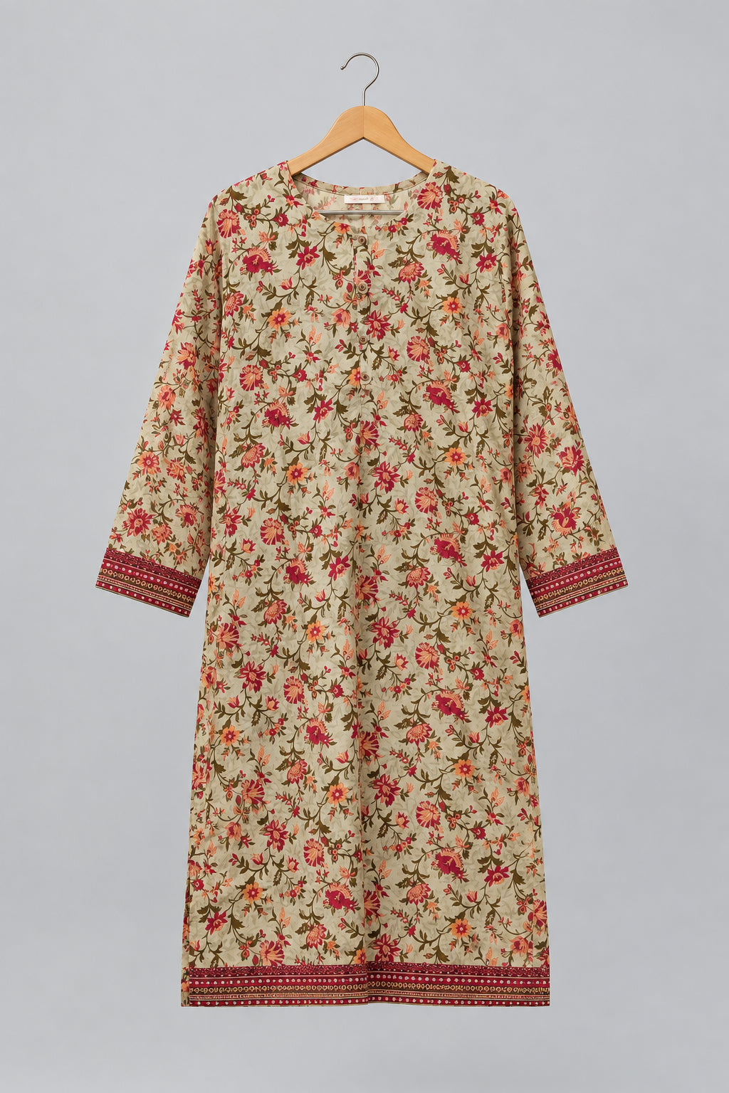 A beige long-sleeve tunic dress with a red and orange floral print and patterned borders, hanging on a black hanger against a white wardrobe door.