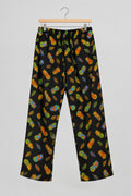 Black pants with a colorful pineapple print, hanging on a metal hanger against a white wardrobe door.