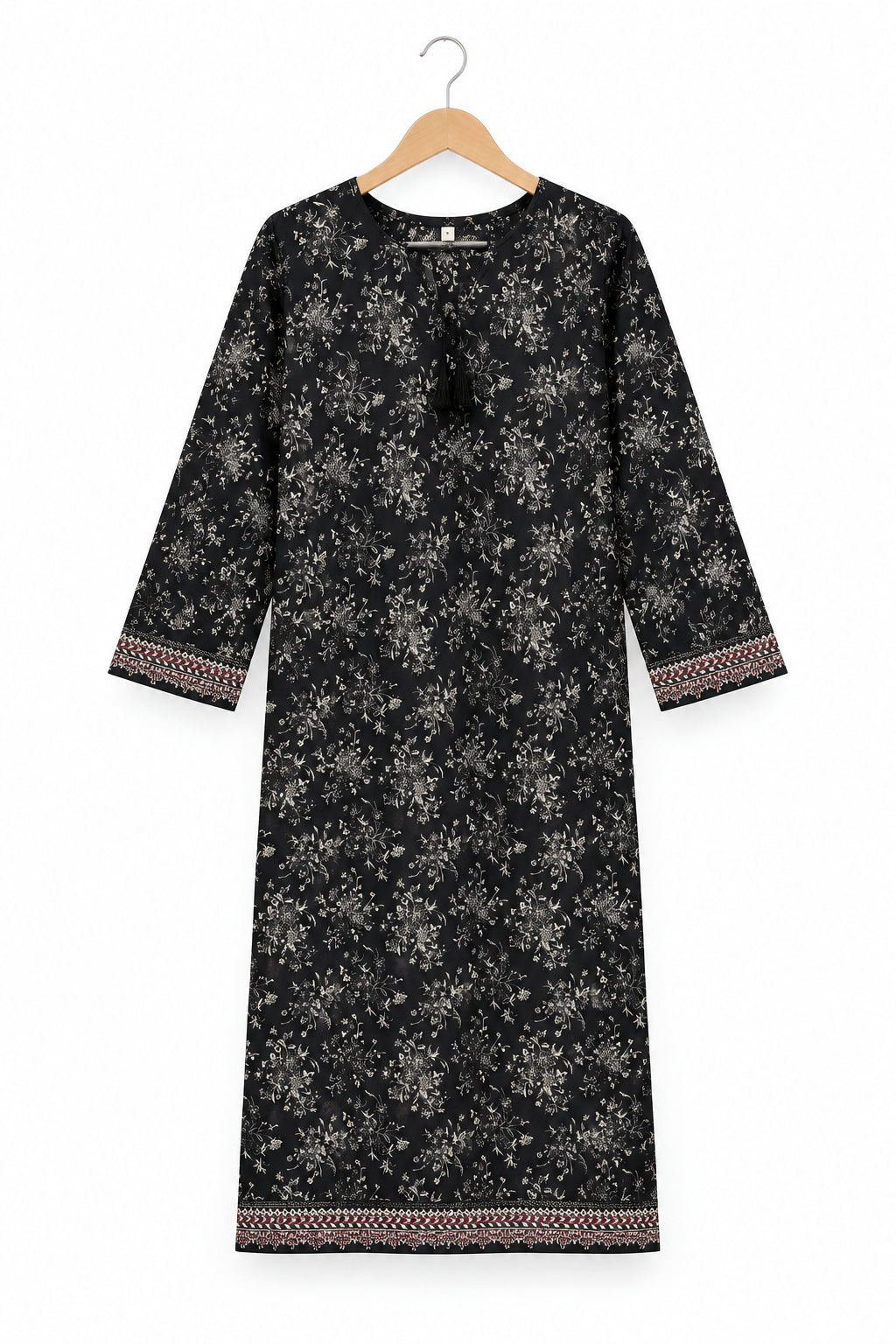 A black three-quarter sleeve tunic dress with a white floral print and patterned trim, hanging on a metal hanger against a white wardrobe door.